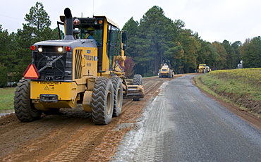 image of road graders scraping a dirt road